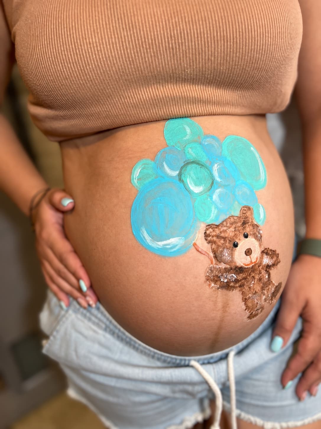 Blue bubbles and a teddy bear painted on an expectant parent's belly