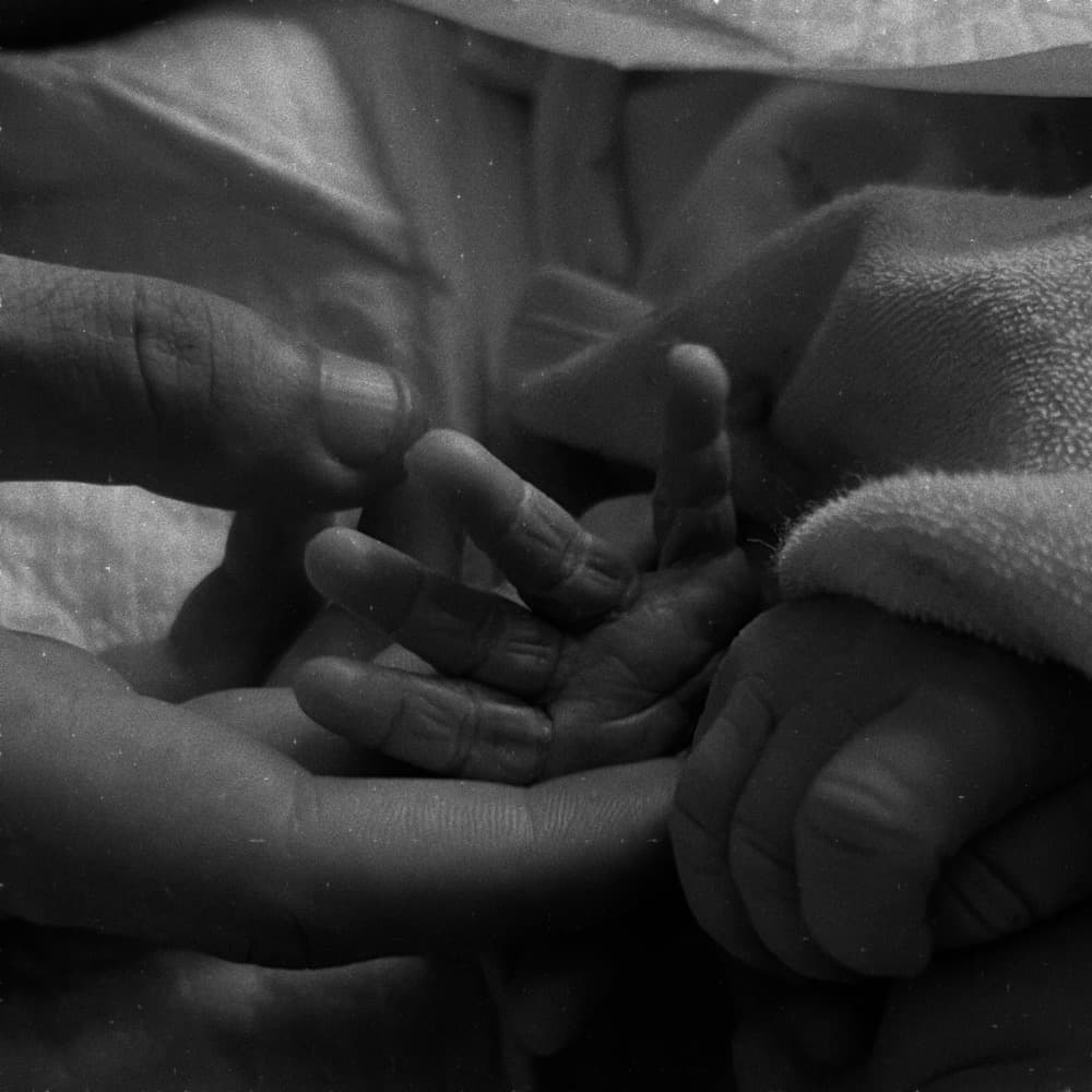 A newborn's feet resting in an adult's hand