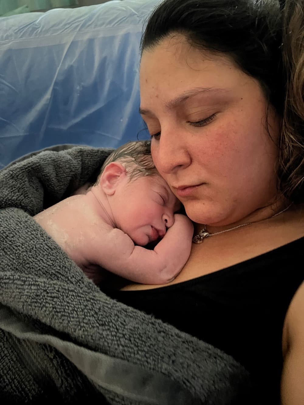 A parent resting with their newborn after birth